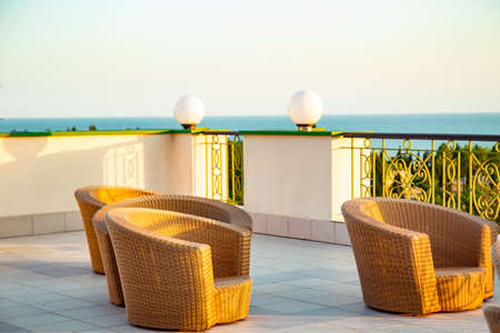 outdoor summer terrace, with stylish rattan furniture, in a cafe at sunsetの写真素材