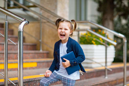 a beautiful little girl, a schoolgirl, in the afternoon near the school, in a school uniform with two ponytailsの写真素材