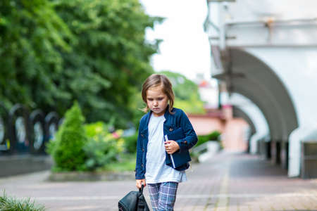 a beautiful little girl, a schoolgirl, in the afternoon near the school, in a stylish school uniformの写真素材