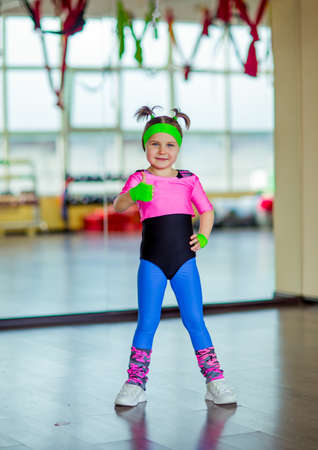 a small, beautiful girl, doing fitness in the gym, in bright, colored sportswearの写真素材
