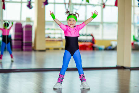 a small, beautiful girl, doing fitness in the gym, in bright, colored sportswearの写真素材