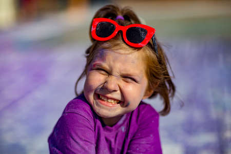 a little, cheerful girl at the Holi festival, in a purple T-shirt, stained with lilac paintの写真素材