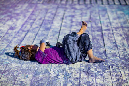 a little, cheerful girl at the Holi festival, in a purple T-shirt, stained with lilac paintの写真素材