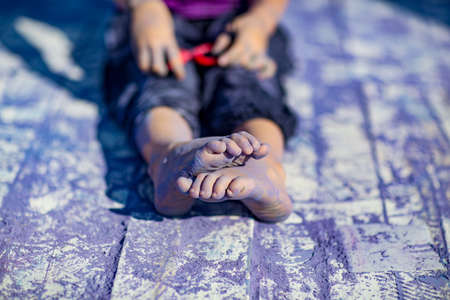 a little, cheerful girl at the Holi festival, in a purple T-shirt, stained with lilac paintの写真素材