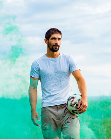 A young, handsome brunette, a football player with a ball in his hand
