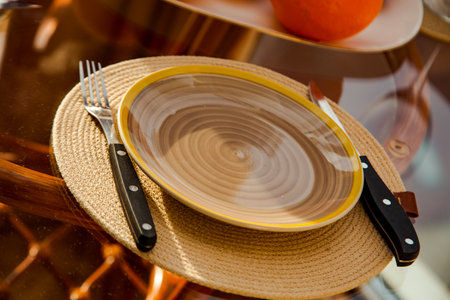 A plate with appliances.fork and knife,on a glass table,close-up