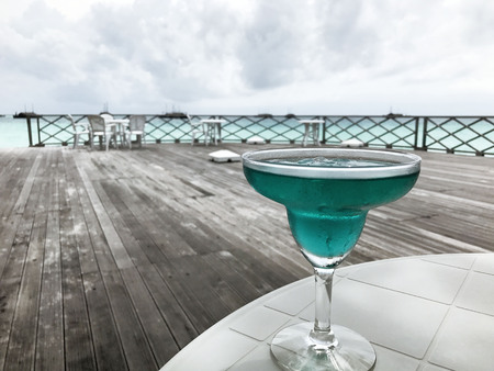 Blue Curacao cocktail on the table beach background - imageの写真素材