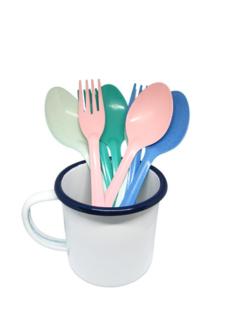 A white enamel cup with many color of spoon and fork isolated on white backgroundの写真素材