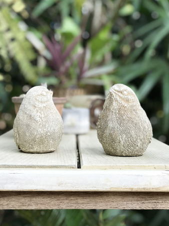 Closeup ceramic bird dolls on the table with garden backgroundの写真素材
