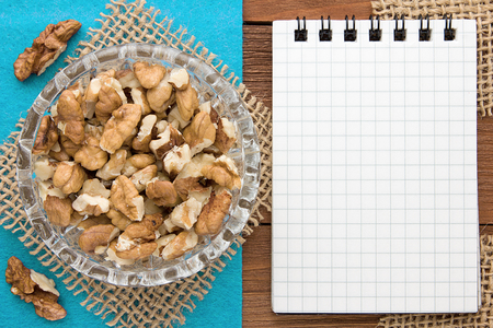 Menu background. Cook book. Recipe notebook with walnuts on a blue background and a wooden board.の写真素材
