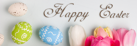 Painted easter eggs and bouquet of spring tulips closeup on a light blue background with space for...