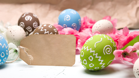 Painted easter eggs and branches of spring sakura closeup on a light blue background with space for congratulationの写真素材