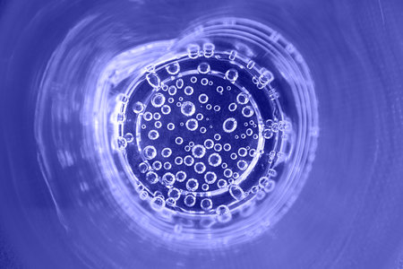 The bubbles of mineral water in a plastic cup close-up. Abstract purple background. Trendy Image, Toned in Color of the year 2022, Very Peri.の写真素材