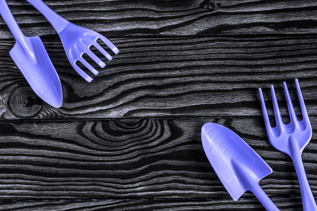gardening tools concept. Spade, rake and fork on wooden background with space for text flat lay top view. Trendy Toned in Color of the year 2022, Very Peri.の写真素材
