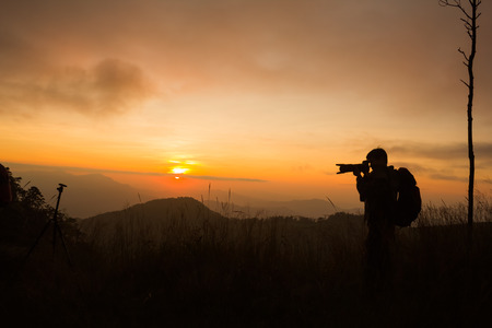 silhouette of photographer taking picture of landscape during sunsetの写真素材