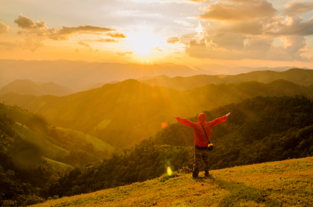 Men, who welcome sunrise with raised hands and enjoying landscapeの写真素材