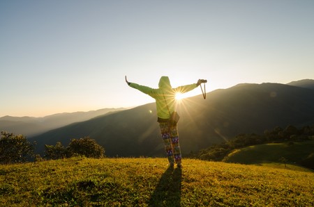 freedom girl with hands up in the mountains against sunの写真素材