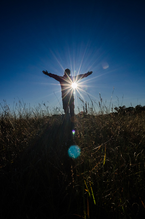 freedom girl with hands up in the mountains against sunの写真素材
