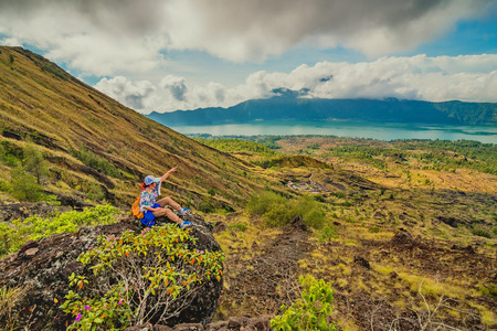 A girl sits on the edge of the cliff and looking at the sun valley and mountainsの写真素材
