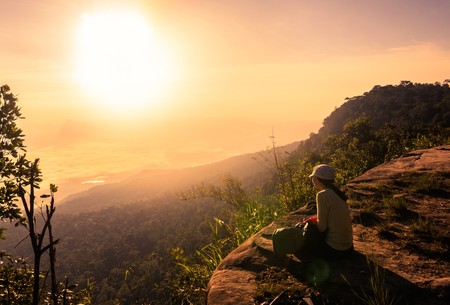 Happy woman sitting on a cliff sideの写真素材
