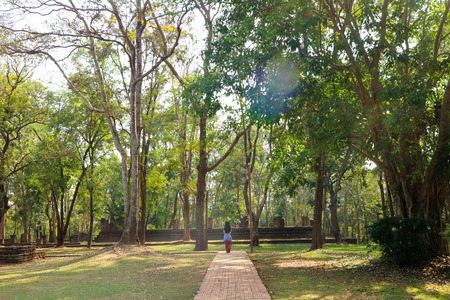 woman walking on sidewalk in Kamphaeng Phet Historical Park, Thailandの写真素材