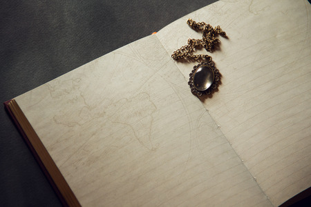 Vintage open book on a black background. vintage pendant on the pages of the old book