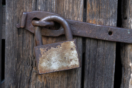 old wooden door locked with rusty padlock. vintage gate to building locked with bolt.の写真素材