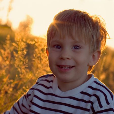 little boy against sunny summer evening landscapeの写真素材