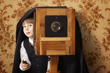 cheerful boy retro photographer with vintage camera over old wallpaper backgroundの写真素材