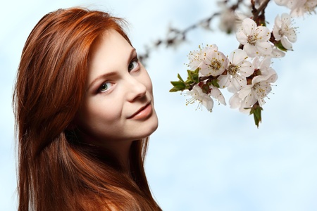 teenager girl beautiful red hair cheerful enjoying over spring flower backgroundの写真素材
