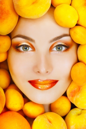 summer portrait of young healty smiling attractive woman with ripe big fresh peaches and apricotsの写真素材