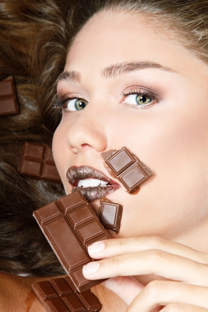 young fresh beautiful woman eating chocolate, beauty female face portrait isolated on white backgroundの写真素材