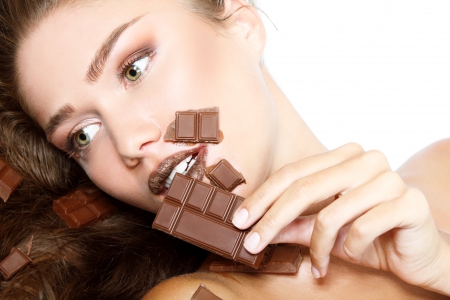 young fresh beautiful woman eating chocolate, beauty female face portrait isolated on white backgroundの写真素材