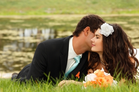 wedding, young bride and groom in love lying on green grass, park summer outdoorの写真素材