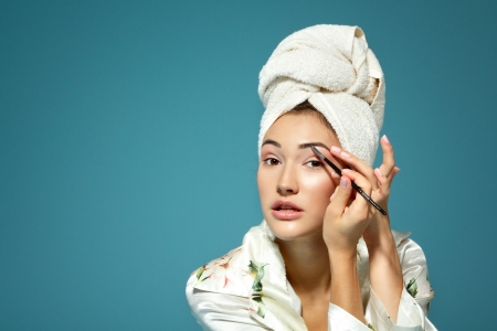 young attractive woman correcting eyebrow over blue background, beauty treatment morning 