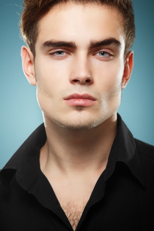 Trendy young man in black shirt, portrait of sexy fashion boy looking right over dark blue backgroundの写真素材
