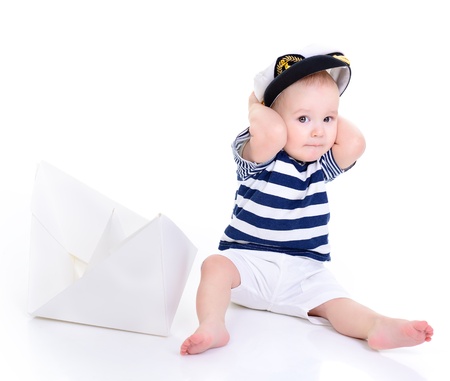 cute baby boy sitting in captain cap with ship of paper - sailor in future, over white backgroundの写真素材