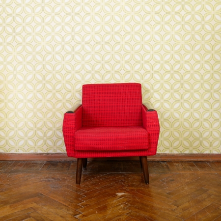 Vintage room with old fashioned red armchair, wallpaper and weathered wooden parquet floor