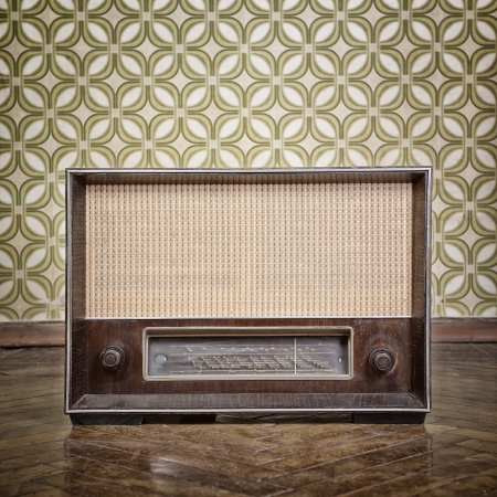 vintage radio receiver device on the weathered wooden parquet floor in vintage room with old fashioned wallpaper, tonedの写真素材