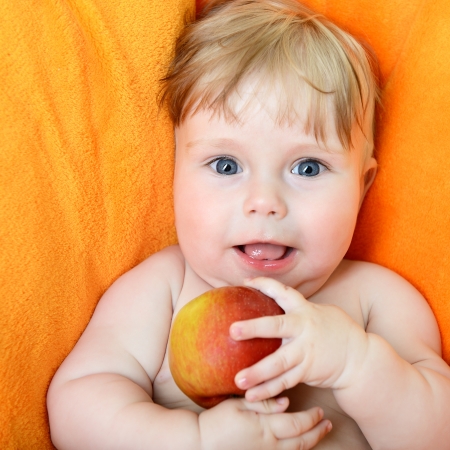 Little baby boy portrait eating red appleの写真素材