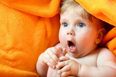 portrait of cute baby boy lying on orange plaid and sucking his leg's fingerの写真素材