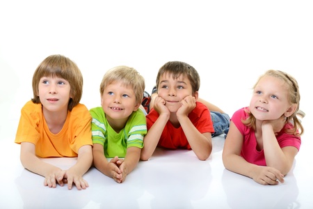 cute children in colored t-shirts lying and smiling looking with interest up in left corner, over white backgroundの写真素材