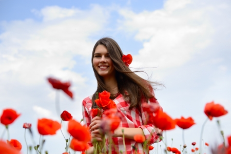 Young beautiful woman on a poppy field, summer outdoor.の写真素材