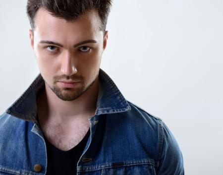 Portrait of handsome young man in jeans jacket, on gray background の写真素材