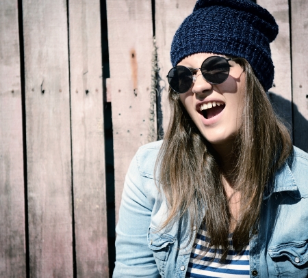 beautiful cool girl in hat and sunglasses against grunge wooden fence, tonedの写真素材