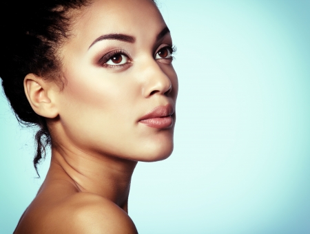 Beauty portrait of young mulatto fresh fashion woman with beautiful makeup, over blueの写真素材