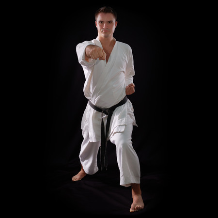 karate man with black belt posing, champion of the world on black background studio shotの写真素材