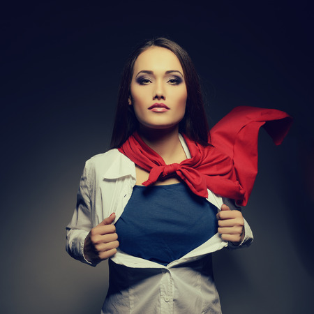 Superwoman. Young pretty woman opening her shirt like a superhero. Super girl, image toned. Beauty saves the world.の写真素材