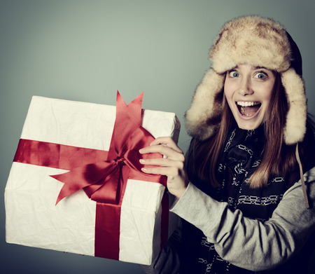 Cute excited christmas girl in winter hat opening gift box, tonedの写真素材