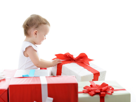 Holidays, baby girl opening box with presents, christmas, birthday, new year, x-mas concept - happy child girl with gift boxes over whiteの写真素材